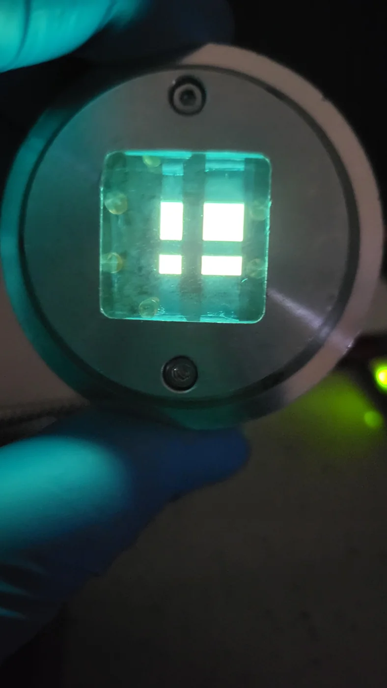 Four emitting OLED pixels on a sample held in a device mount
